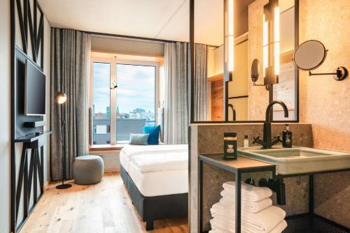 Habitación de hotel con baño con lavabo y cama en me and all hotel Kiel, part of JdV by Hyatt en Kiel