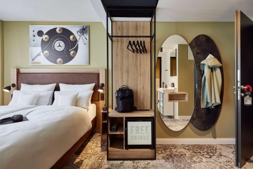 - une chambre d'hôtel avec un lit et un miroir dans l'établissement me and all hotel Hanover, part of JdV by Hyatt, à Hanovre