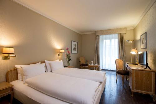 a hotel room with a large white bed and a television at Grand Hotel Beau Rivage Interlaken in Interlaken