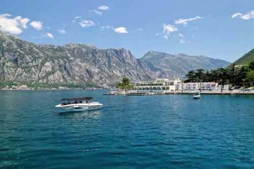 a boat in the water with mountains in the background at Hyatt Regency Kotor Bay Resort in Kotor