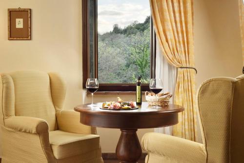 a table with two chairs and a window with wine glasses at Relais Villa Monte Solare Wellness & SPA in Panicale