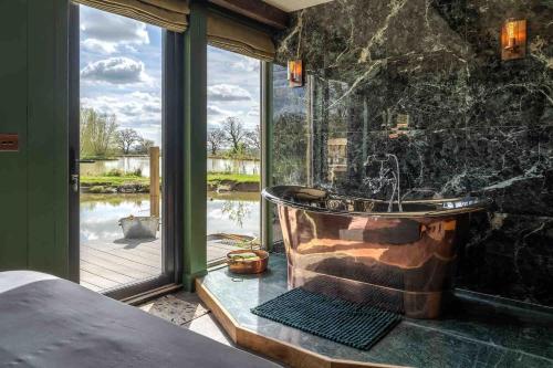 uma casa de banho com uma grande banheira e uma grande janela. em Waters edge em Cucklington