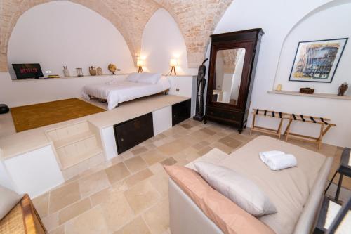 a bedroom with a bed and a couch and a mirror at Dimora del Vico - Exclusive Terrace with View in Cisternino