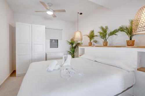 una camera da letto bianca con un letto con lenzuola bianche e pantofole di Good Mood - Sunny Seaview a Callao Salvaje