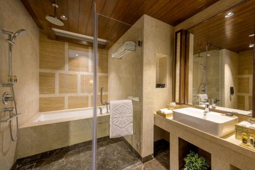 ein Bad mit einem Waschbecken und einer Dusche in der Unterkunft Taj Gandhinagar Resort and Spa in Gandhinagar