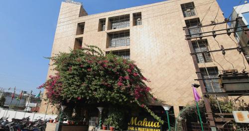 a building with a flowering bush in front of it at Capital O Hotel Kartik in Jabalpur