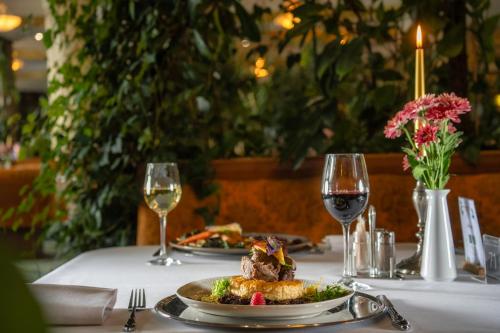 a table with a plate of food and two glasses of wine at Hotel Gołębiewski Karpacz in Karpacz