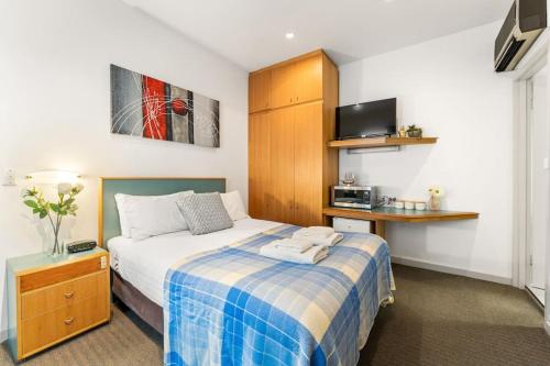 a bedroom with a bed with a blue and white blanket at The Hidden Gem - Adelaide CBD in Adelaide