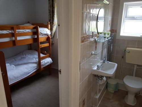 łazienka z umywalką, toaletą i łóżkami piętrowymi w obiekcie Barclay Court Guest House w mieście Torquay