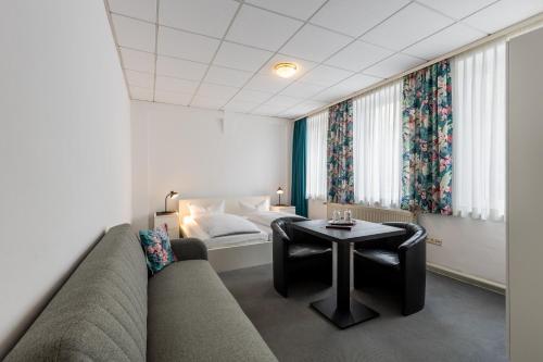 a hotel room with a couch and a bed and a table at Hotel Annet garni in Meerane