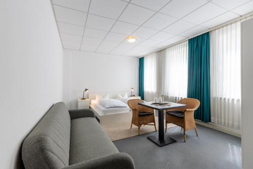 a living room with a couch and a table and a bed at Hotel Annet garni in Meerane