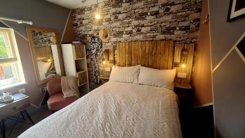 ein Schlafzimmer mit einem Bett und einer Ziegelwand in der Unterkunft Willow Studio in Telford