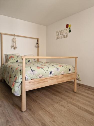 a bed with a wooden frame in a room at CASAS BEM HAJA Casa da Praça in São Miguel de Acha