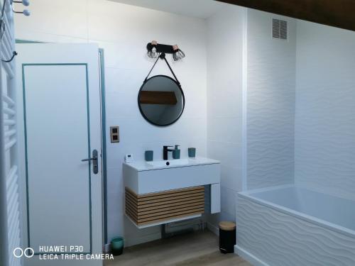 uma casa de banho com um lavatório, um espelho e uma banheira em 2 chambres privatives avec Sdb proche circuit em Arnage