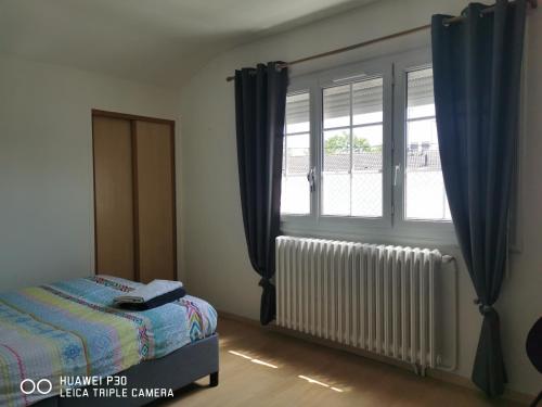 een slaapkamer met een bed en een raam met blauwe gordijnen bij 2 chambres privatives avec Sdb proche circuit in Arnage