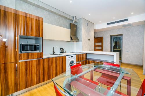 Una cocina con una mesa de cristal y sillas rojas. en Baku İn Front of hotel apartment, en Baku