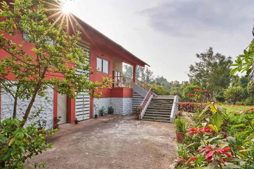 a red building with a staircase next to a yard at StayVista's Amoda Villa - Near Venna Lake, Amidst Farmland with Jacuzzi and Indoor Activities in Mahabaleshwar