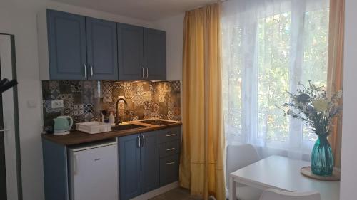 a kitchen with blue cabinets and a table and a window at Family Hotel Sofi in Sozopol