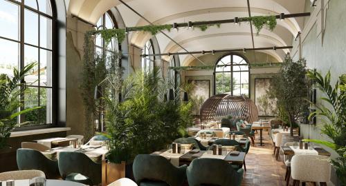 ein Restaurant mit Tischen, Stühlen und Pflanzen in der Unterkunft Borgo Dei Conti Resort Relais & Chateaux in Monte Petriolo