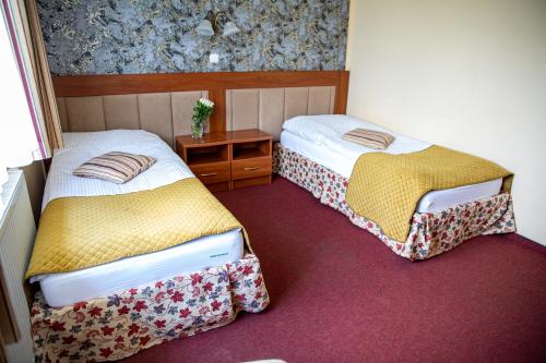 a room with two beds and a night stand at Hotel pod Wierzba in Świdnica
