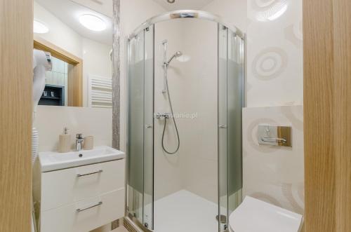 a bathroom with a shower and a sink at Villa Łeba Pokoje & Apartamenty in Łeba