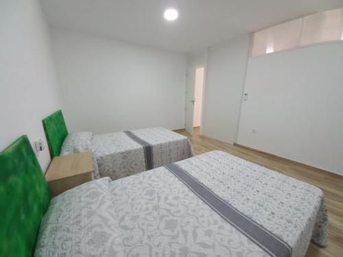 two beds in a room with white walls and wooden floors at Bazan Apartaments2 in Alicante