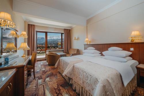 a hotel room with two beds and a desk and a window at Hotel Gołębiewski Karpacz in Karpacz