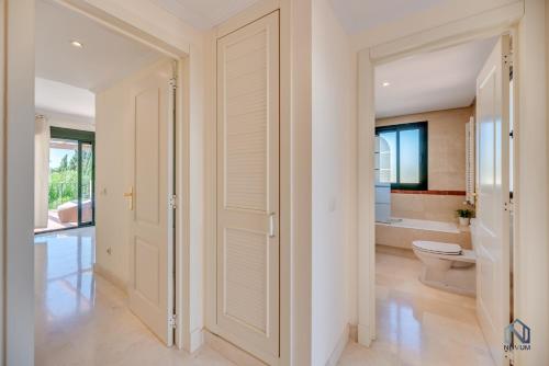 a white bathroom with a toilet and a sink at Modern and Spacious 2 BDRM Penthouse - 3 Pools and Sea Views in Marbella