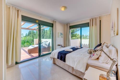 a bedroom with a bed and a large window at Modern and Spacious 2 BDRM Penthouse - 3 Pools and Sea Views in Marbella