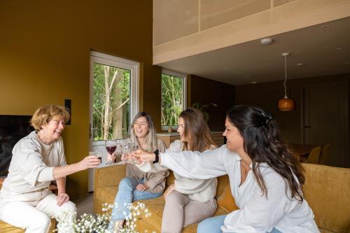 a group of women sitting on a couch holding wine glasses at Residenties en bungalow Royal Domburg in Domburg