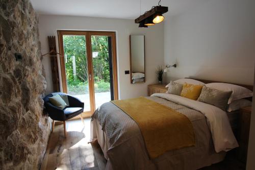 a bedroom with a bed and a chair and a window at The Vila Bled Premium Luxury Retreat in Bled
