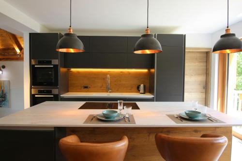a kitchen with black cabinets and a large island with chairs at The Vila Bled Premium Luxury Retreat in Bled