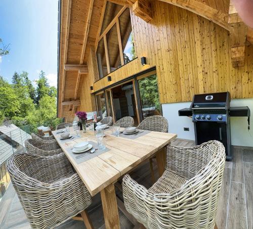 a wooden table and chairs on a patio with a stove at The Vila Bled Premium Luxury Retreat in Bled