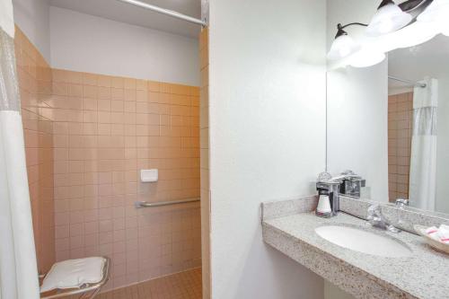 Un baño con lavabo y ducha con espejo. en Baymont by Wyndham Coalinga, en Coalinga