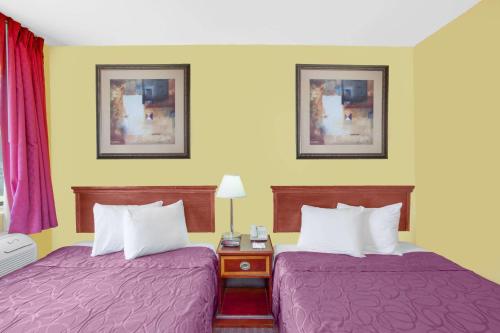 2 bedden in een hotelkamer met paarse lakens bij Baymont by Wyndham Coalinga in Coalinga