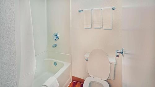 a white bathroom with a toilet and a bath tub at Suites Los Angeles CA Los Angeles LAX in Inglewood