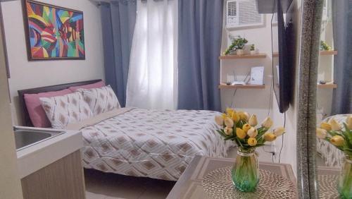 um pequeno quarto com uma cama e um vaso de flores em JJMC PLACE 22f em Manila