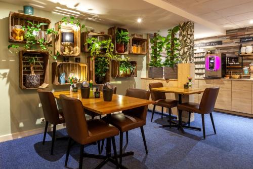 a restaurant with two tables and chairs and plants on the wall at Amsterdam Hotel Uithoorn in Uithoorn
