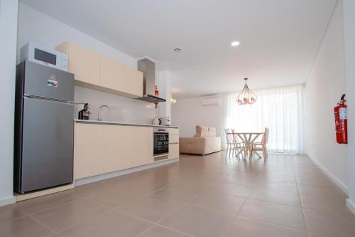 a white kitchen with a refrigerator and a table at Chalês - Maria Alva in Marialva