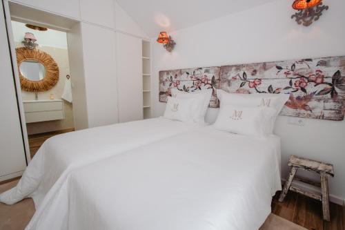 a white bedroom with a white bed with a floral wallpaper at Chalês - Maria Alva in Marialva
