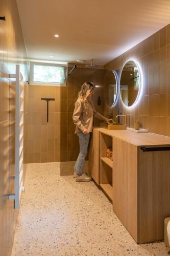 a woman standing in a bathroom with a sink at Residenties en bungalow Royal Domburg in Domburg