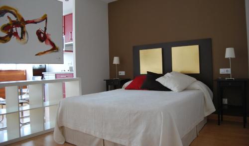 una camera da letto con un letto con lenzuola bianche e cuscini rossi di Apartamentos Plaza Mayor a Llanes