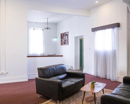 a living room with a leather couch and a table at The Beaconsfield Hotel in Fremantle
