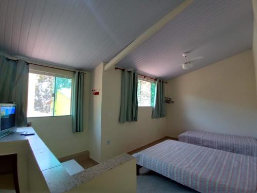 um quarto com uma cama, uma televisão e janelas em Casa á Beira-Mar Praião, Prainha, Barra de São João em Barra de São João