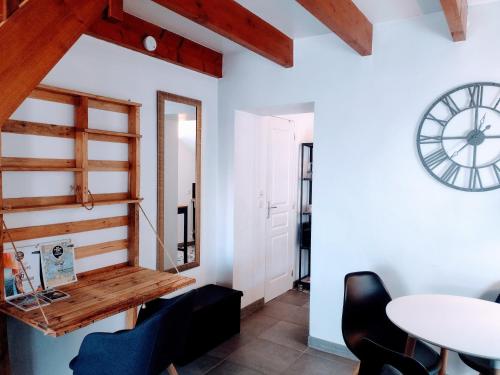 Zimmer mit einem Tisch, Stühlen und einer Uhr in der Unterkunft Le Duplex, parking wifi aux portes de vannes in Vannes