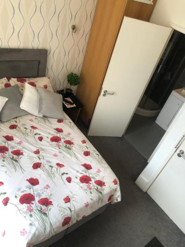 a bedroom with a bed with red flowers on it at Cosy Studio Apartment - Blackheath, Greenwich in London