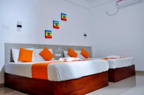 a bedroom with two beds with orange and white pillows at Super King Star Holiday Resort in Anuradhapura