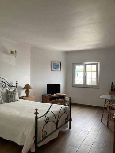 a bedroom with a bed and a desk and a window at Casa da Nazaré in Portinho da Arrábida