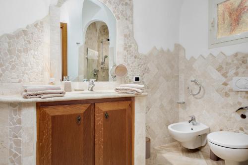 a bathroom with a sink and a toilet and a mirror at Appartamento Eleganza - SHERDENIA Luxury Apartments in Marinella