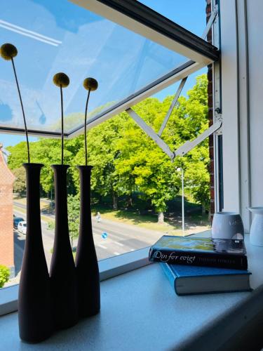 a window sill with three vases with flowers in them at Scandinavian Apartment Hotel - Prison Museum 2 - one room apartment in Horsens